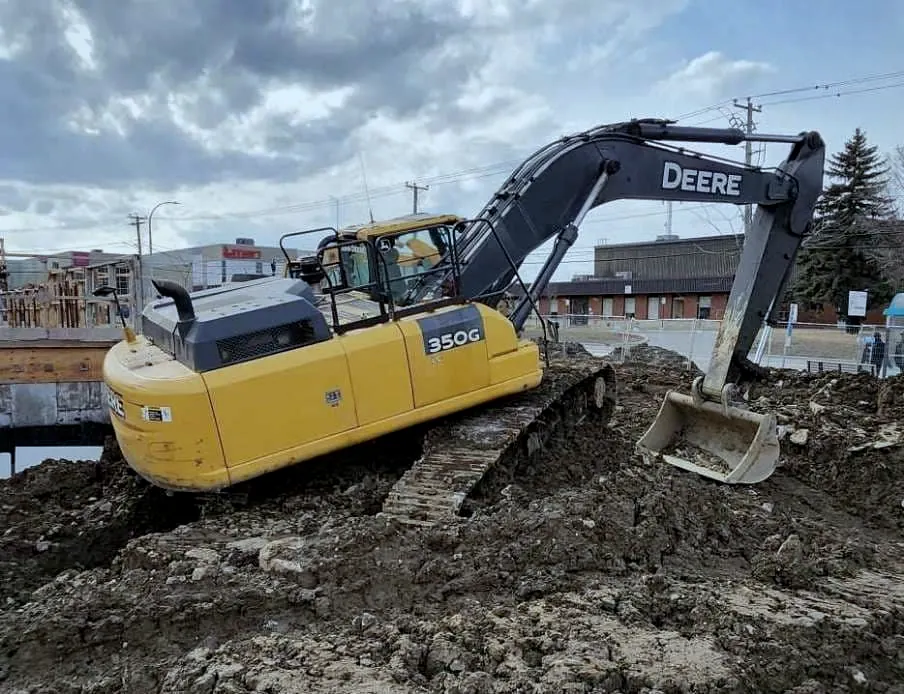Excavatrice Deere 350G en réparation sur un chantier urbain.