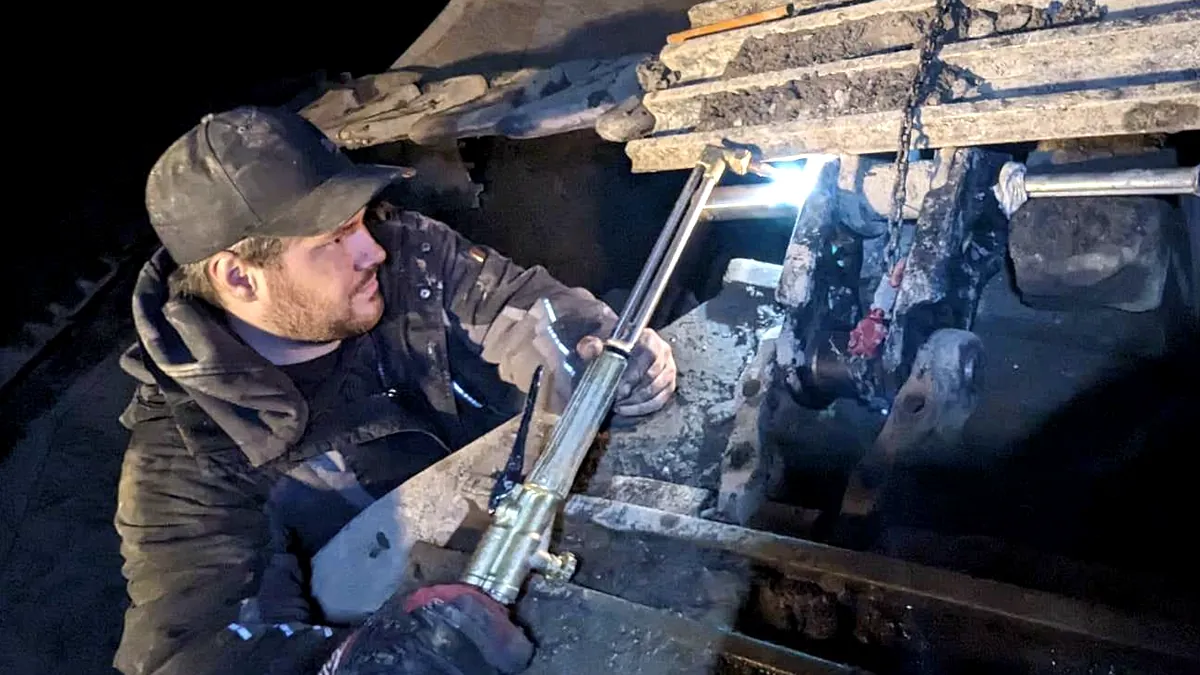 Dave Vallières coupe au chalumeau une pièce d'excavatrice, de nuit, sur le chantier.